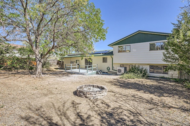 rear view of property with fence, an outdoor fire pit, ac unit, a patio area, and roof mounted solar panels