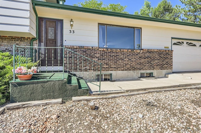 view of exterior entry with brick siding and a garage