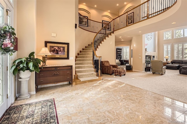 entrance foyer with marble finish floor, a high ceiling, baseboards, and stairway