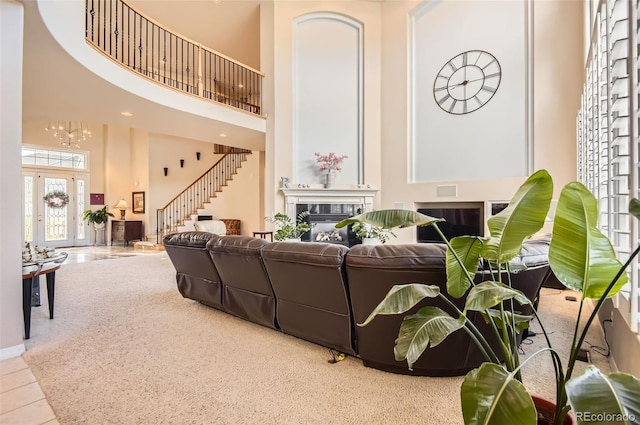 living area featuring a high ceiling, a fireplace, stairs, and a notable chandelier