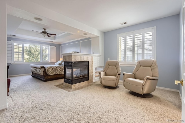 bedroom featuring visible vents, a tiled fireplace, baseboards, carpet floors, and a tray ceiling