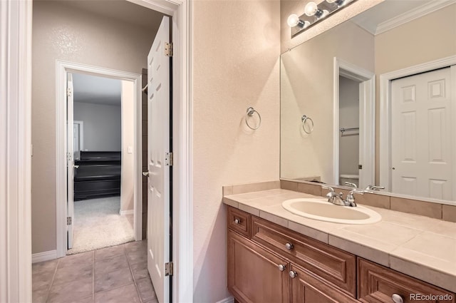 bathroom with vanity, ornamental molding, a textured wall, tile patterned flooring, and toilet