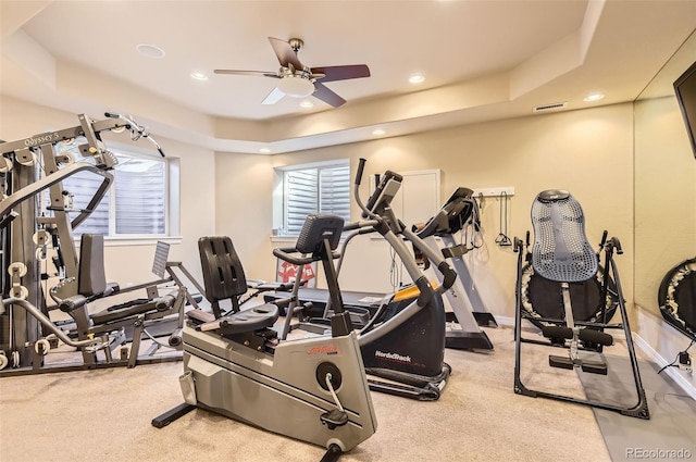 workout area featuring recessed lighting, a ceiling fan, and a tray ceiling
