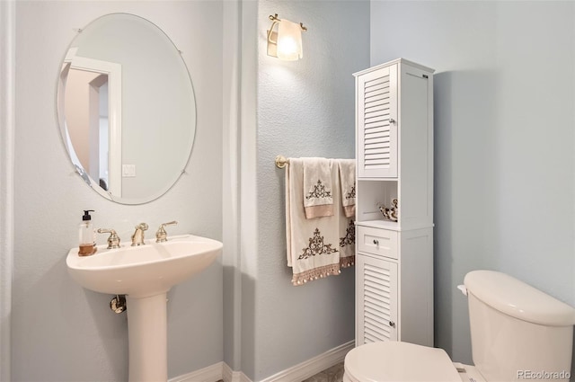 bathroom with baseboards, a sink, and toilet