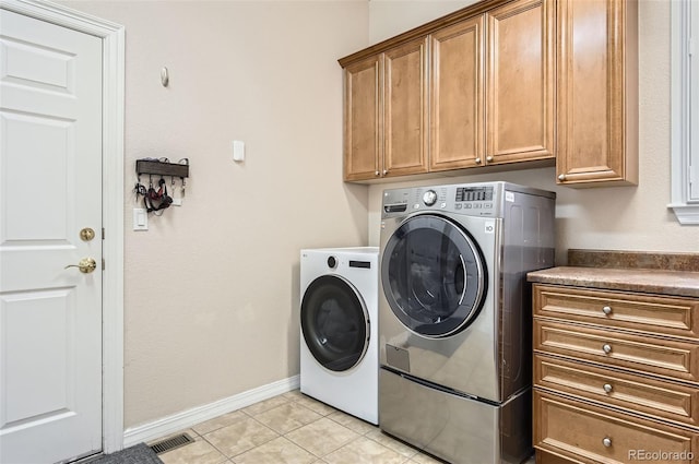 laundry area with visible vents, baseboards, separate washer and dryer, cabinet space, and light tile patterned floors