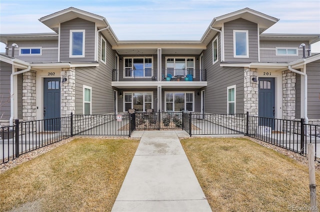 view of property featuring a balcony, a front yard, and fence