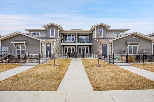 view of front of home featuring a fenced front yard, a balcony, and a standing seam roof