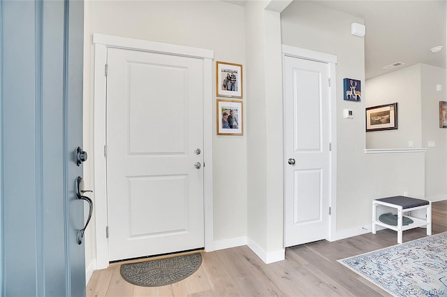 foyer entrance featuring baseboards, visible vents, and light wood finished floors