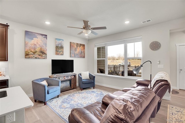 living area with visible vents, baseboards, ceiling fan, and light wood finished floors