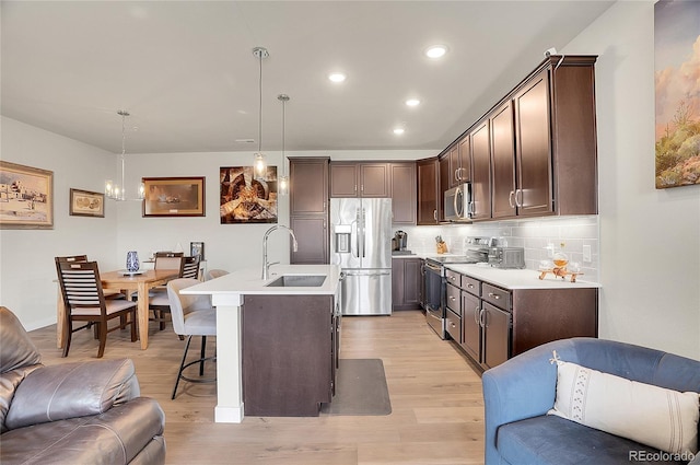 kitchen with a sink, open floor plan, stainless steel appliances, a breakfast bar area, and dark brown cabinets