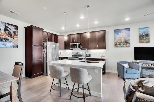 kitchen featuring visible vents, open floor plan, light countertops, stainless steel appliances, and a sink