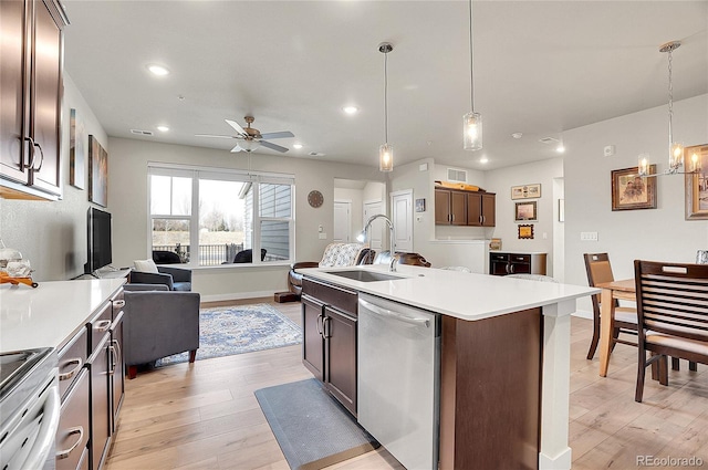 kitchen featuring light wood-style flooring, a sink, stainless steel appliances, light countertops, and open floor plan