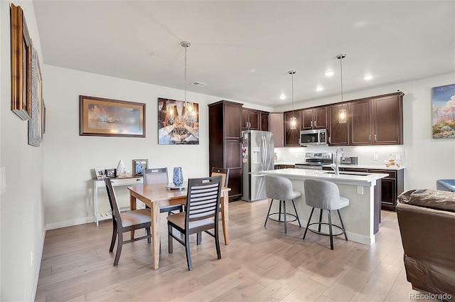 kitchen featuring dark brown cabinetry, stainless steel appliances, light countertops, and light wood-style floors