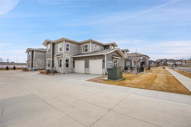 view of front of home with a residential view, central AC, a garage, stone siding, and driveway