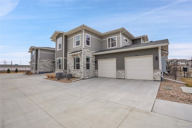 prairie-style home featuring central AC unit, concrete driveway, an attached garage, and fence