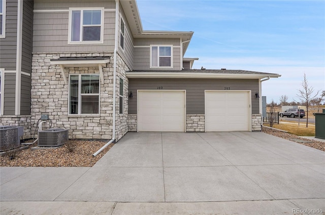 view of front of home with stone siding, driveway, and central AC