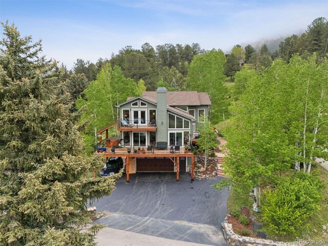 4230 S Meadow Brook Ln, Evergreen, CO 80439 - view of front of house featuring driveway, a wooden deck, a forest view, a chimney, and a garage