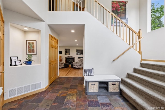 4230 S Meadow Brook Ln, Evergreen, CO 80439 - foyer entrance featuring stairway, stone tile flooring, a wood stove, a high ceiling, and baseboards
