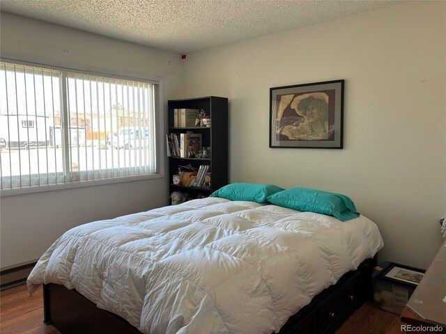 bedroom featuring a baseboard radiator, a textured ceiling, and wood finished floors