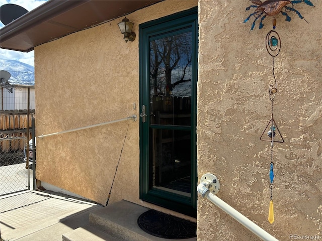 entrance to property with fence and stucco siding