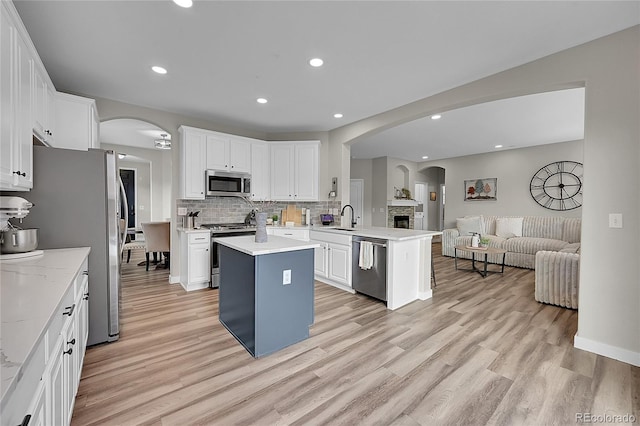 kitchen with stainless steel appliances, sink, a kitchen island, and white cabinets