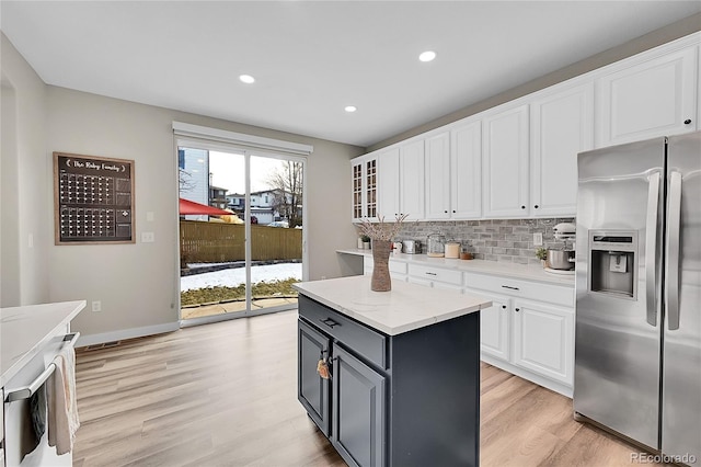 kitchen featuring tasteful backsplash, white cabinetry, a center island, stainless steel refrigerator with ice dispenser, and light hardwood / wood-style flooring