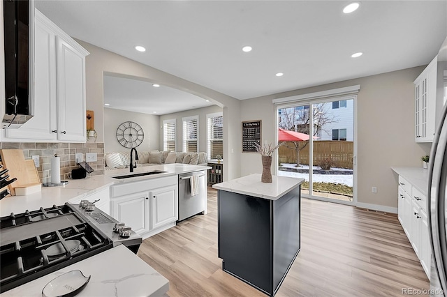 kitchen featuring sink, light stone counters, light hardwood / wood-style floors, white cabinets, and stainless steel dishwasher