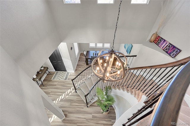 stairs featuring an inviting chandelier and wood-type flooring