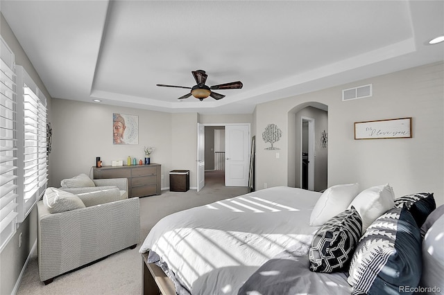 carpeted bedroom featuring a tray ceiling and ceiling fan