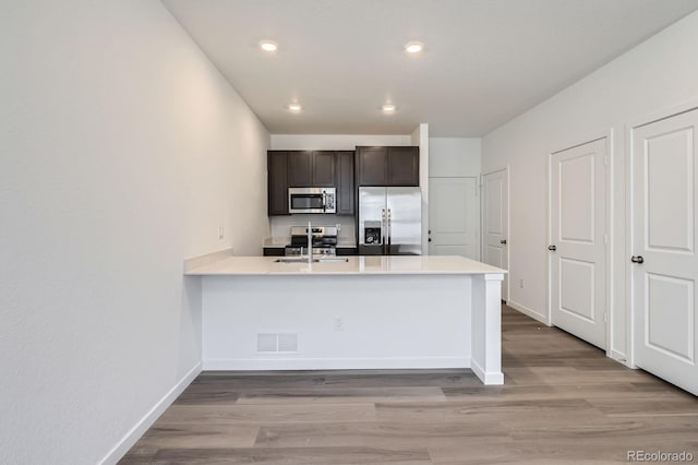 1986 S Haleyville Way, Aurora, CO 80018 - kitchen with appliances with stainless steel finishes, light wood finished floors, light countertops, a peninsula, and recessed lighting