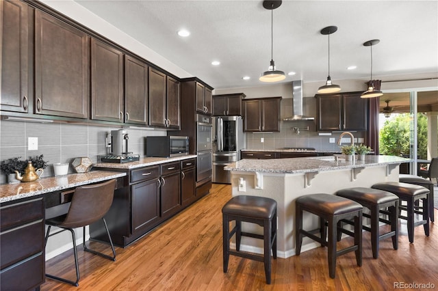 1852 E Sea Drift Dr, Windsor, CO 80550 - kitchen with wall chimney range hood, stainless steel appliances, tasteful backsplash, dark brown cabinetry, and recessed lighting