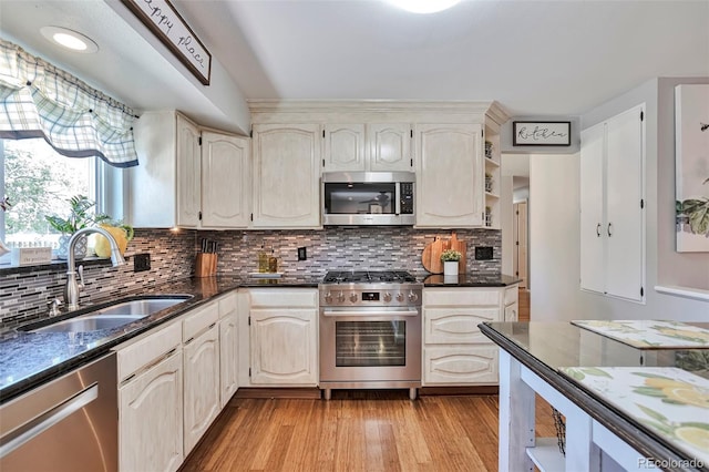 8262 Otis Ct, Arvada, CO 80003 - kitchen featuring appliances with stainless steel finishes, backsplash, light wood-type flooring, and dark stone counters