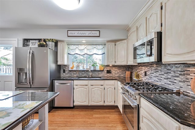 8262 Otis Ct, Arvada, CO 80003 - kitchen with stainless steel appliances, healthy amount of natural light, dark stone counters, and light wood finished floors