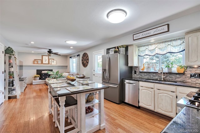 8262 Otis Ct, Arvada, CO 80003 - kitchen with stainless steel appliances, backsplash, light wood-style flooring, ceiling fan, and open floor plan