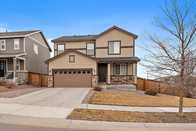 view of front of property featuring stone siding, fence, driveway, and an attached garage