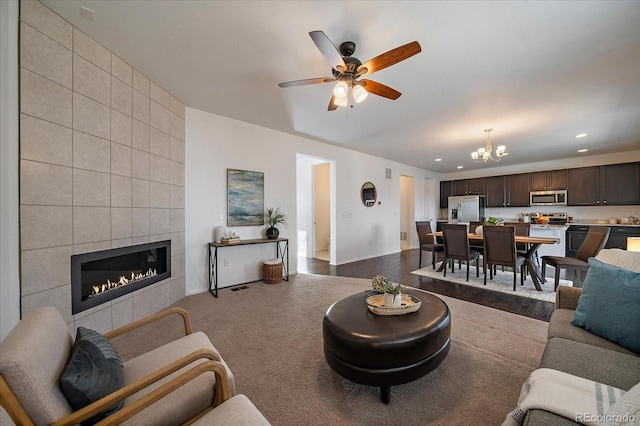 living area featuring carpet, a fireplace, recessed lighting, baseboards, and ceiling fan with notable chandelier