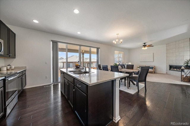 kitchen featuring appliances with stainless steel finishes, dark wood-type flooring, a fireplace, and a sink