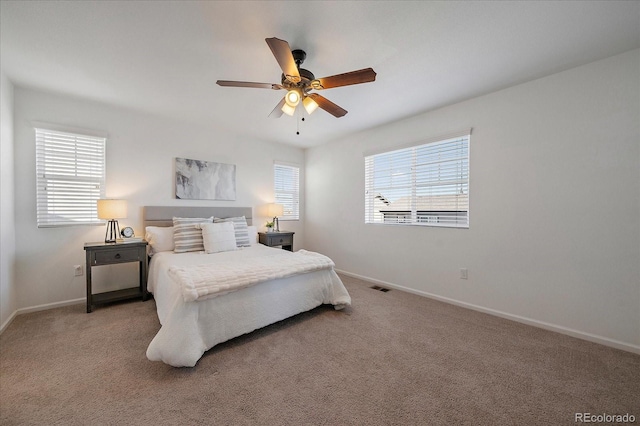 carpeted bedroom featuring a ceiling fan, visible vents, and baseboards