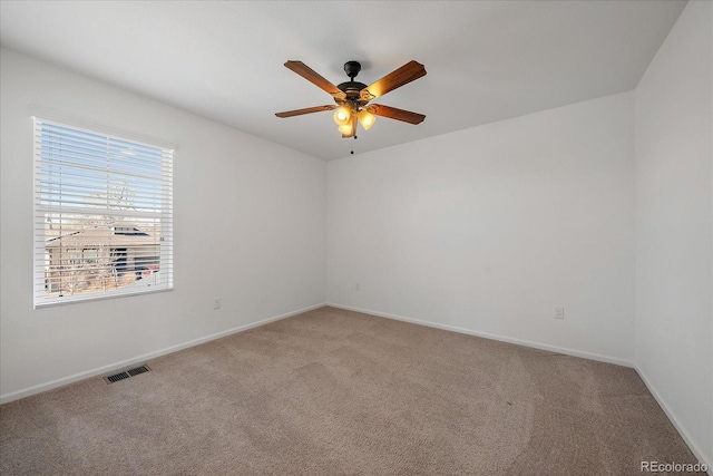 spare room featuring ceiling fan, visible vents, baseboards, and light colored carpet