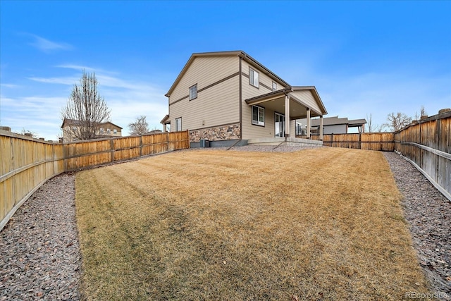 back of house with a fenced backyard and a yard