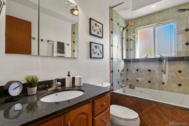 295 E Amherst Ave, Englewood, CO 80113 - bathroom featuring tiled shower / bath combo, vanity, a textured wall, and toilet