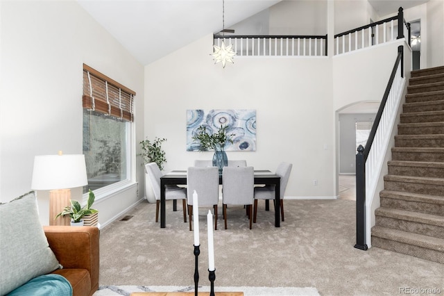 dining area with stairway, baseboards, high vaulted ceiling, arched walkways, and carpet flooring