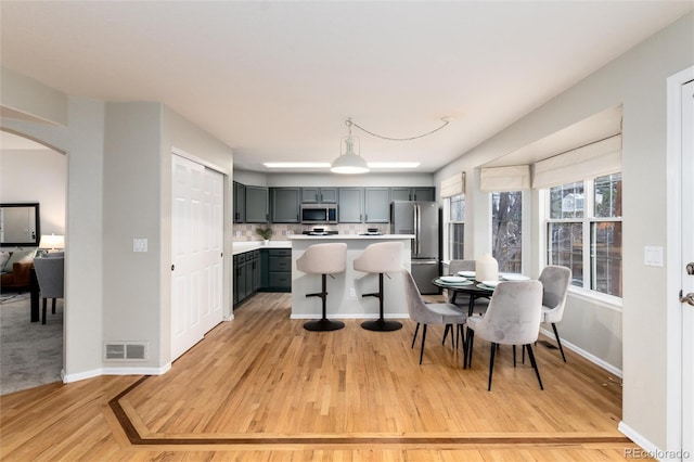 kitchen featuring light wood-type flooring, visible vents, stainless steel appliances, arched walkways, and light countertops