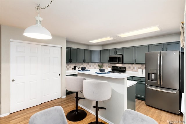 kitchen with a kitchen bar, light wood-style flooring, stainless steel appliances, and light countertops