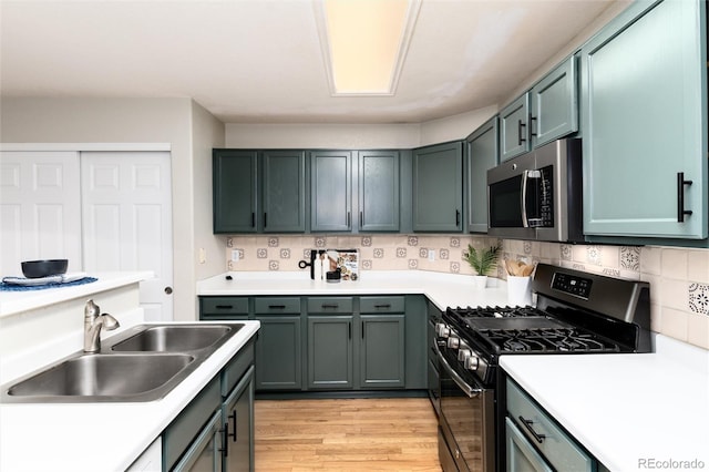 kitchen with light wood-type flooring, a sink, tasteful backsplash, stainless steel appliances, and light countertops