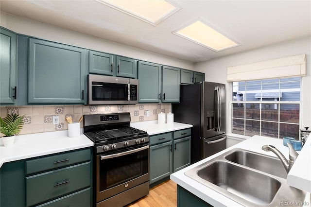 kitchen featuring light countertops, backsplash, appliances with stainless steel finishes, and a sink