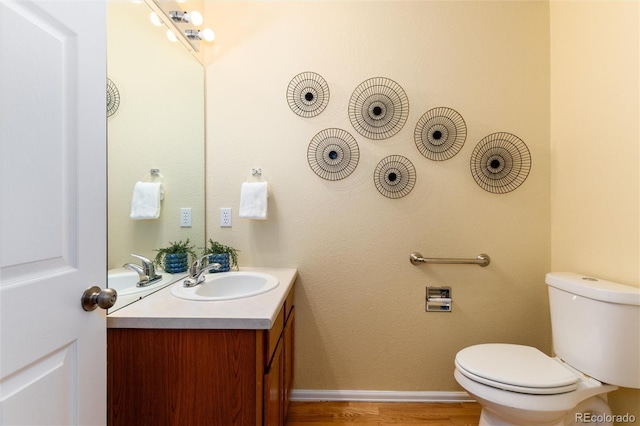 bathroom featuring vanity, toilet, wood finished floors, and baseboards