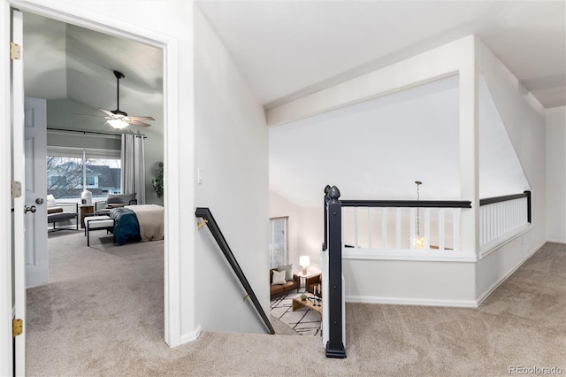 hall featuring lofted ceiling, carpet flooring, an upstairs landing, and baseboards