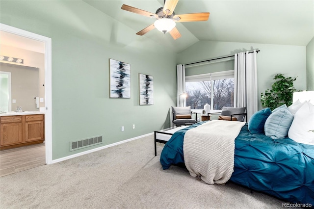 bedroom with visible vents, baseboards, lofted ceiling, light carpet, and ensuite bath