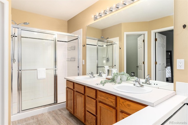 full bath with a shower stall, double vanity, and a sink